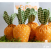 Close up of a white washed planter box filled with green moss and fabric carrots with a sign in the background that reads 