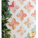 Close-up of a quilt featuring pink and peach floral patterns with white stitching amidst green leaves.