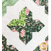 Colorful quilt featuring a floral and green patchwork design, with intricate stitching patterns.