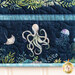 A quilted fabric featuring an octopus, jellyfish, and aquatic plants on a dark blue background.