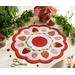 A white countertop with foliage and a houseplant in the background with a white and red strawberry themed table topper with notions and a jar of strawberries in the background