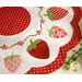 Close up of June table topper showing white and red fabric and floral embroidery detail with strawberry shaped applique