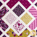 Close up of quilt blocks made up of intersecting white lines and purple and yellow floral fabrics