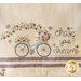 A decorative towel featuring a vintage bicycle with a basket of flowers, surrounded by butterflies and hearts. The text Chase your dreams is artistically written nearby.