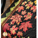 Close up photo of the Autumn Allure quilt showing applique leaf details and a zig zag pattern sewn into the border