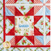 Close up of one quadrant of the quilt showing a sawtooth star in red fabric with strawberry themed blue and cream fabrics