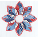 Leaf shaped table topper with central opening containing a floral centerpiece. Topper is made of red white and blue patriotic fabrics.