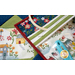 An assortment of colorful fabric squares featuring floral and house patterns, alongside an embroidery hoop and a light blue sewing tool on a textured background.