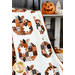 Close up photo of a quilt featuring rows of blocks with patchwork pumpkins made with orange, cream, and black fabrics. Quilt is draped in the foreground with Halloween decor in the background