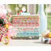 Stack of pink, yellow, peach, green, blue, and grey fabrics on a table with flowers