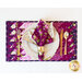 A beautifully set dining table featuring a vibrant purple placemat adorned with floral patterns. The setting includes a white plate, a folded floral napkin, a gold napkin ring, a fork, and a knife, all arranged neatly.