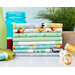 A stack of colorful fabric bundles arranged neatly on a table. The fabrics feature various playful patterns, including animals and playful designs. In the background, there are spools of thread and a green plant, with a blue jar partially visible.