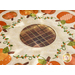 Close up photo of a scalloped table mat with pumpkins in a ring and embroidered details around a brown plaid circle at the center