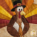 Close up photo of the finished paper piecing block showing stitching and fabric details of a cartoon turkey wearing a tie and capotain