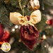 Close up photo of a pocket angel ornament made with the Stof Christmas 2023 fabric collection hanging on a decorated and lit Christmas tree in the background