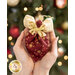 Close up photo of a pocket angel ornament made with the Stof Christmas 2023 fabric collection being held in someone's cupped hands with a decorated and lit Christmas tree in the background