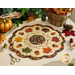 Photo of an autumn themed table topper on a white table with fall decor all around including leaves, a gold pumpkin, and sewing notions