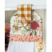 Close up photo of a white kitchen towel with floral and gingham fabrics