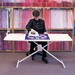 woman ironing on an ironing board  in front of purple and pink fabric