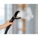 A hand holding a steam cleaner with steam visibly emitting from the nozzle.