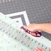 person using a rotary cutter to cut fabric on a foldable cutting mat