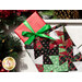 Close up photo of a Christmas stocking made with red, green, black, and white Christmas fabrics hanging from a white mantle with garland all around and a red wrapped gift inside the stocking.