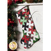 Photo of a Christmas stocking made with red, green, black, and white Christmas fabrics hanging from a white mantle with garland all around