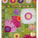 Close up photo of a floral quilt showing applique details of large pink, purple and white daisies with a patchwork green background
