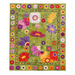 Isolated photo of a large, floral quilt made with green patchwork batiks, and large, colorful applique flowers, on a white background