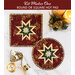 Top down photo of a pair of red hot pads made with metallic Christmas fabric on a white countertop with gold silverware, candles and decor on either side with the words 