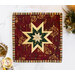 Close up photo of red square hot pad on a white countertop with a candle, silverware wrapped in a decorative napkin, and pinecone winter decor