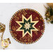 Close up photo of a red circlular hot pad on a white countertop with a candle, silverware wrapped in a decorative napkin, and pinecone winter decor