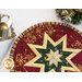 Close up photo of a red circlular hot pad on a white countertop with silverware wrapped in a decorative napkin, and pinecone winter decor