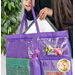 Close up image of someone holding the tote and pulling out a wafer 3 lightbox with the pockets filled with notions like thread spools and scissors for scale 