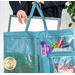 A woman holds a turquoise crafting tote with transparent pockets displaying crafting supplies while she puts a light box into the tote.