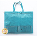 The back of the teal tote, showing one very large vinyl pocket with a creative grids ruler laying over top to show scale.