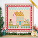 A colorful quilt depicting a colorful house with flowers, and a picket fence.