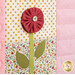 Close up of patchwork quilt featuring a decorative flower with pink petals and green leaves on floral and polka-dotted fabrics.