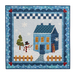 A winter-themed quilt featuring a blue house with orange windows, a snowman in a black hat and red scarf, a green tree, and a fence, all surrounded by snowflakes. The quilt has a decorative border with hearts and a checkered pattern at the top.