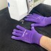 The machine quilting gloves in action, palm side down, moving a black quilt around a sewing machine