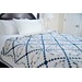 A blue monochromatic quilt featuring a geometric design on a made bed.