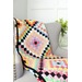 A colorful quilt with around the world blocks drapped over a chair