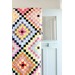 A colorful quilt with around the world blocks drapped over a door