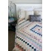 A neatly made bed with a colorful around the world quilt.