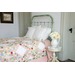 A vintage bed made with a pink patchwork quilt.