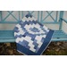 A blue and white quilt draped over a bench, with a zigzag pattern.