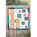 A colorful quilt featuring a giraffe design surrounded by geometric patterns on a fence backdrop.