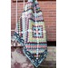 A colorful around the world quilt draped over a railing, featuring a diamond pattern in various hues.