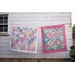 Two colorful quilts displayed against a white wooden wall