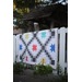 A grey chain quilt featuring colorful stars displayed on a white fence.